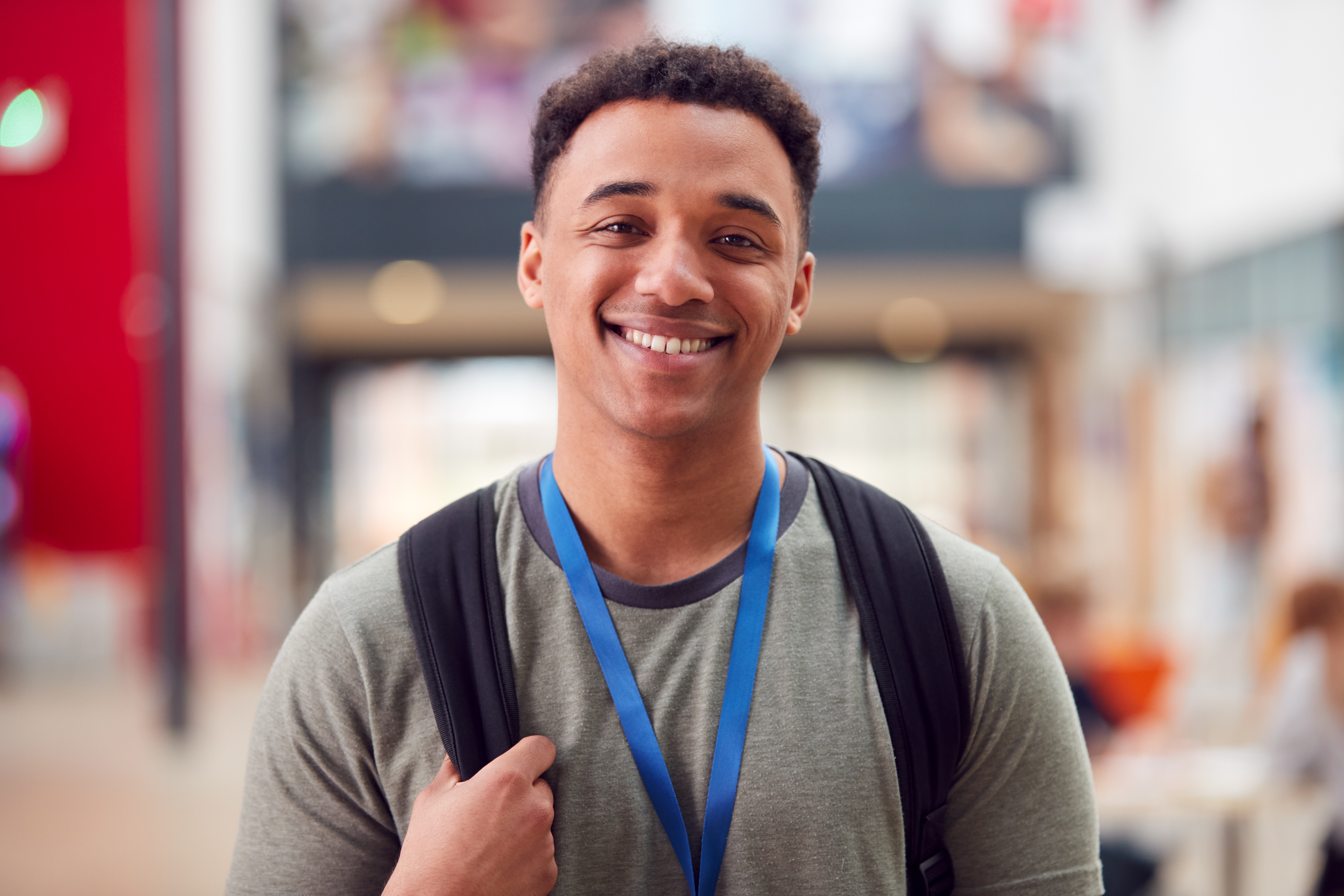 Male student with blue lanyard and backpack smiling