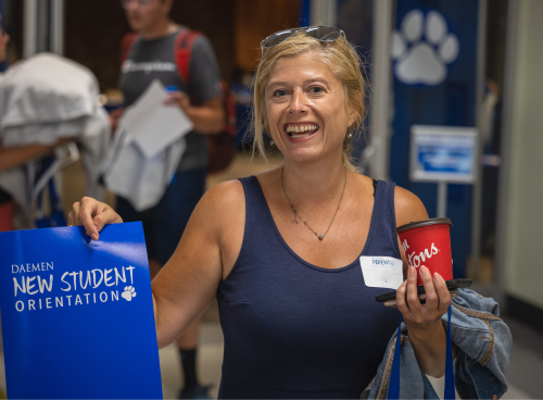 Mother holding new student orientation folder and smiling 