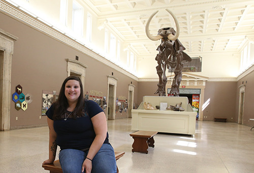 Female student at natural history museum in front of woolly mammoth skeleton
