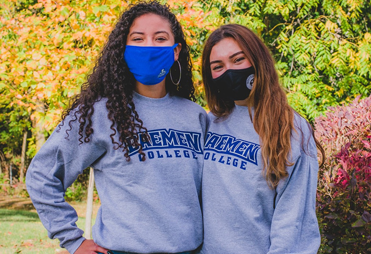 Two female students in masks wearing Daemen sweatshirts outside