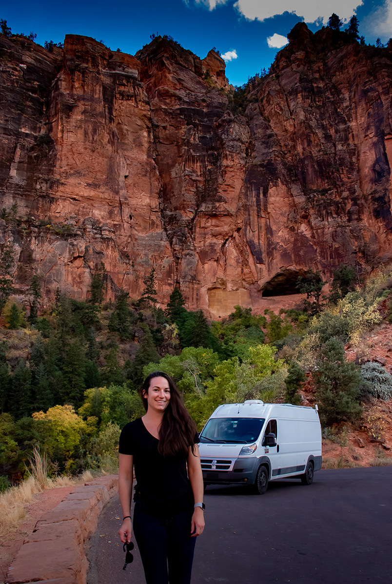 Jess standing on a road in a canyon in black scrubs