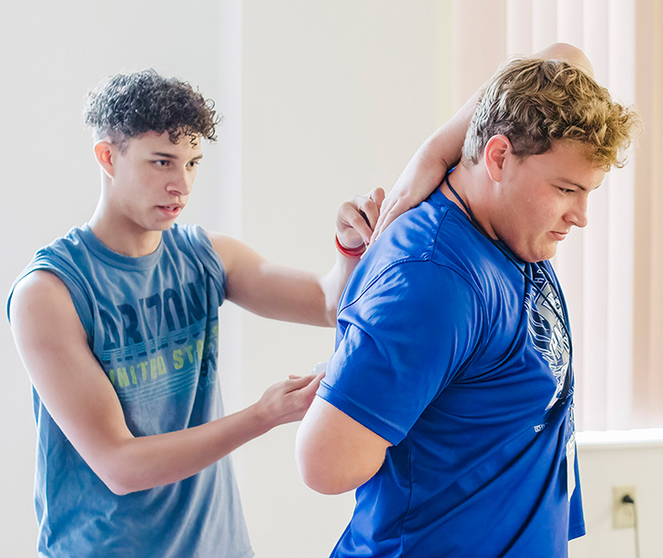 Two students stretching with arms behind their back