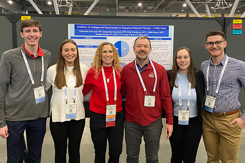 Professors at CSM standing in front of poster