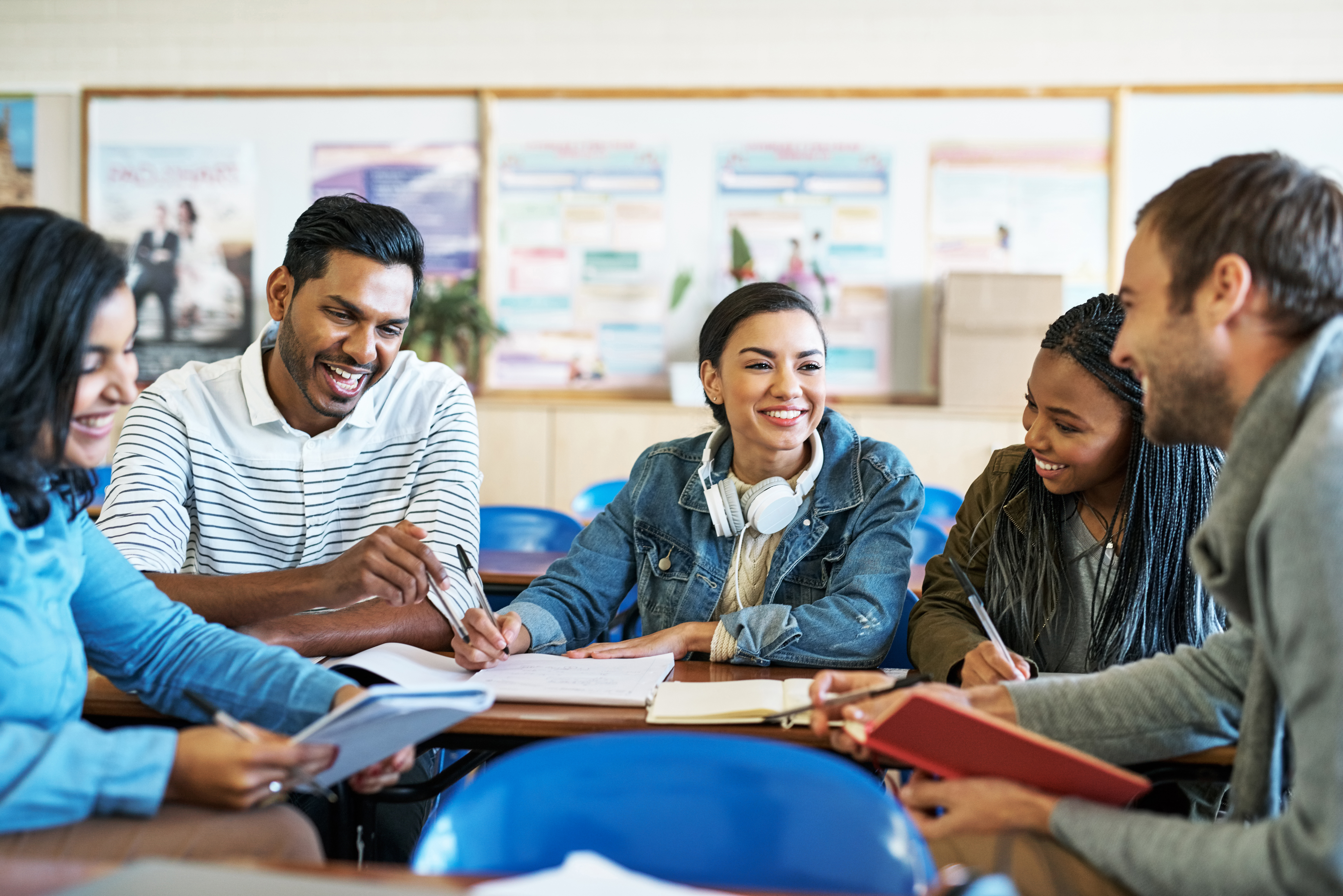 Five college students sitting at a table interacting with each other