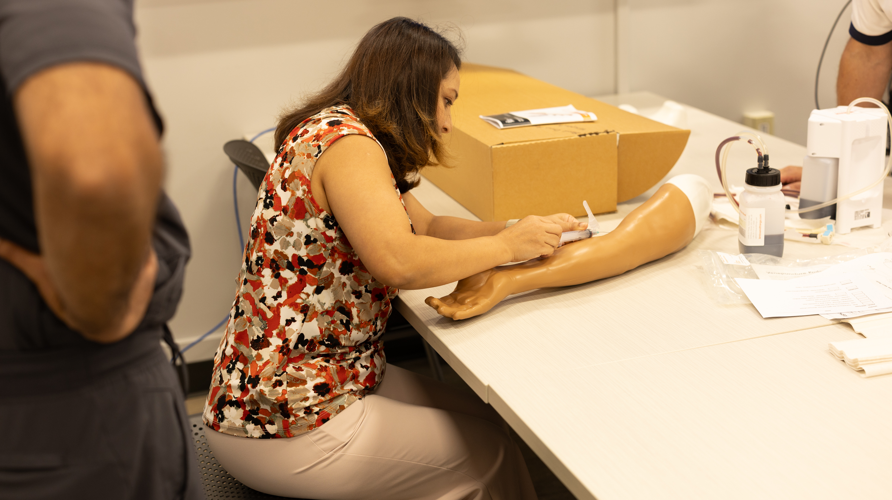 Student practicing inserting a needle on a mannequins arm