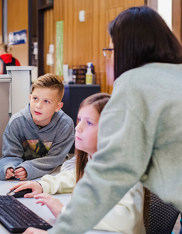 Therapist helping two kids working on a computer in Daemen RIC