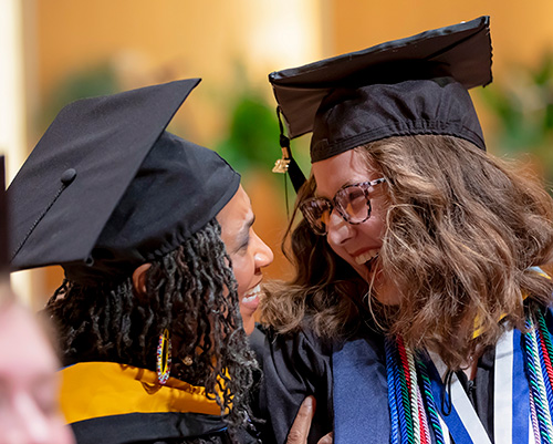 Tiffany Hamilton and student in cap and gown at commencement smiling 