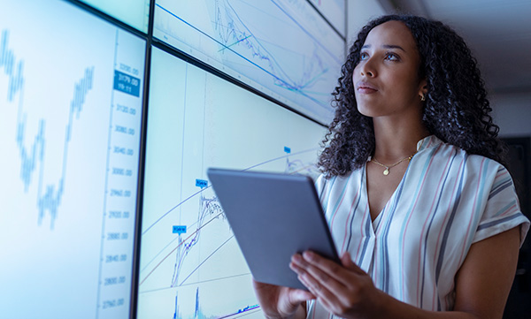 Female student holding a tablet looking at data on screens