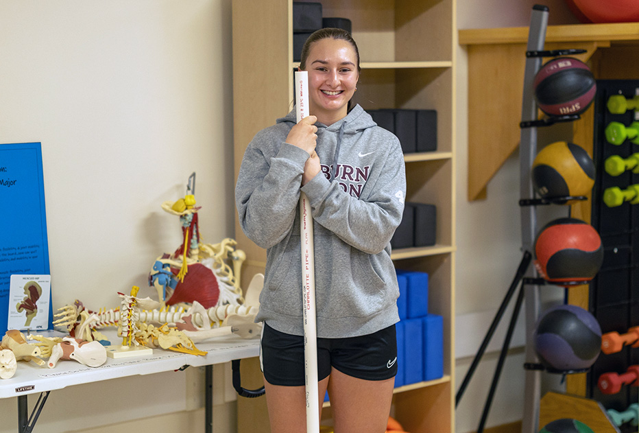 Female student in PT lab holding a stick
