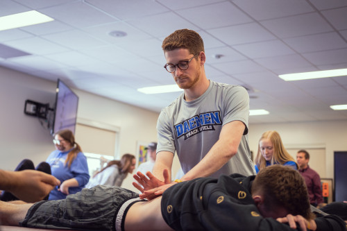 Physical Therapy student working on a students lower back who is laying down