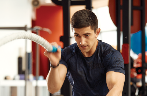 Person in gym working out using heavy ropes