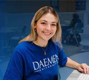 Daemen student smiling at the camera while sitting. 